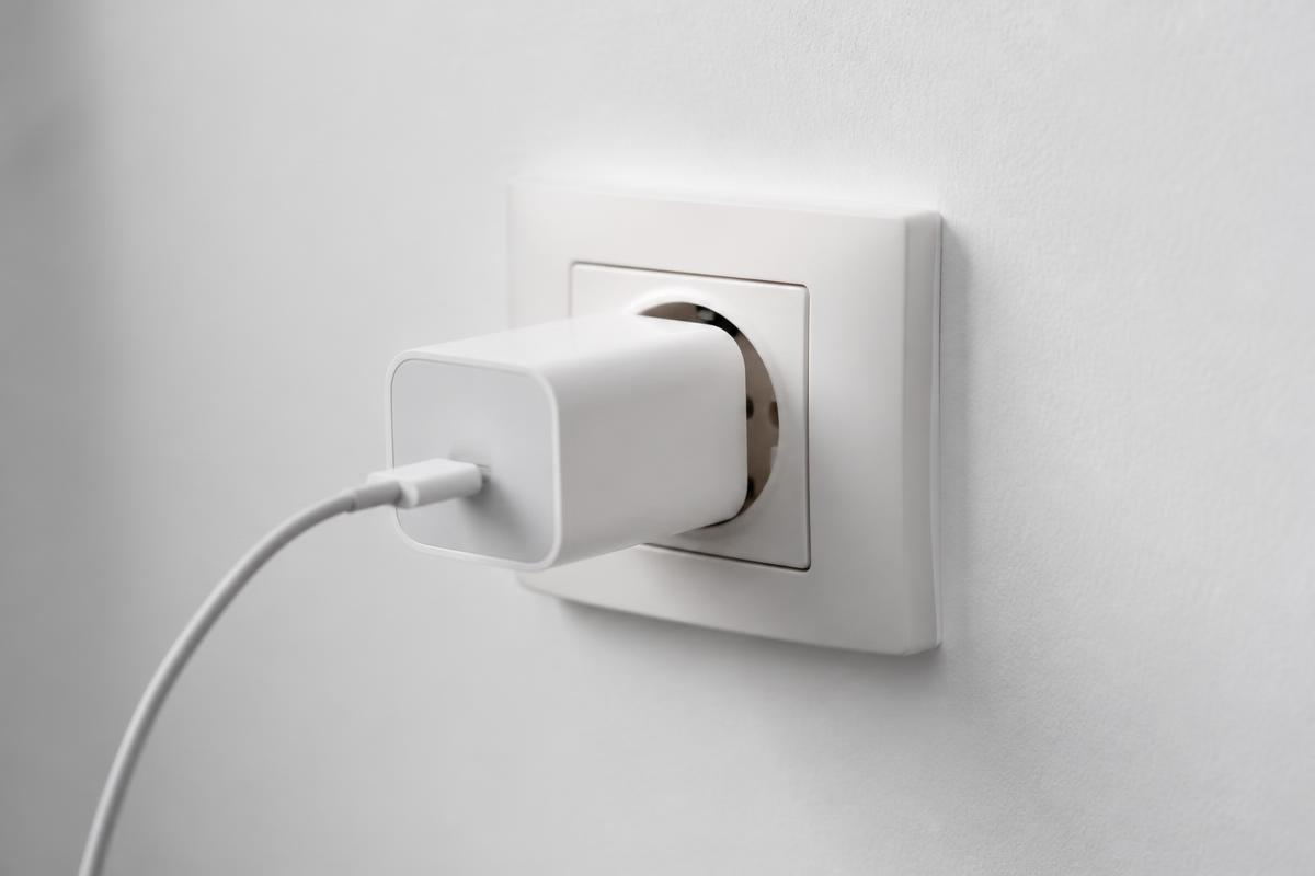 Chargeur GaN USB-C compact branché sur une prise murale — illustration de l'article « Sigles chargeur (PD, QC, PPS) : ce qu'ils veulent dire en 2026 »